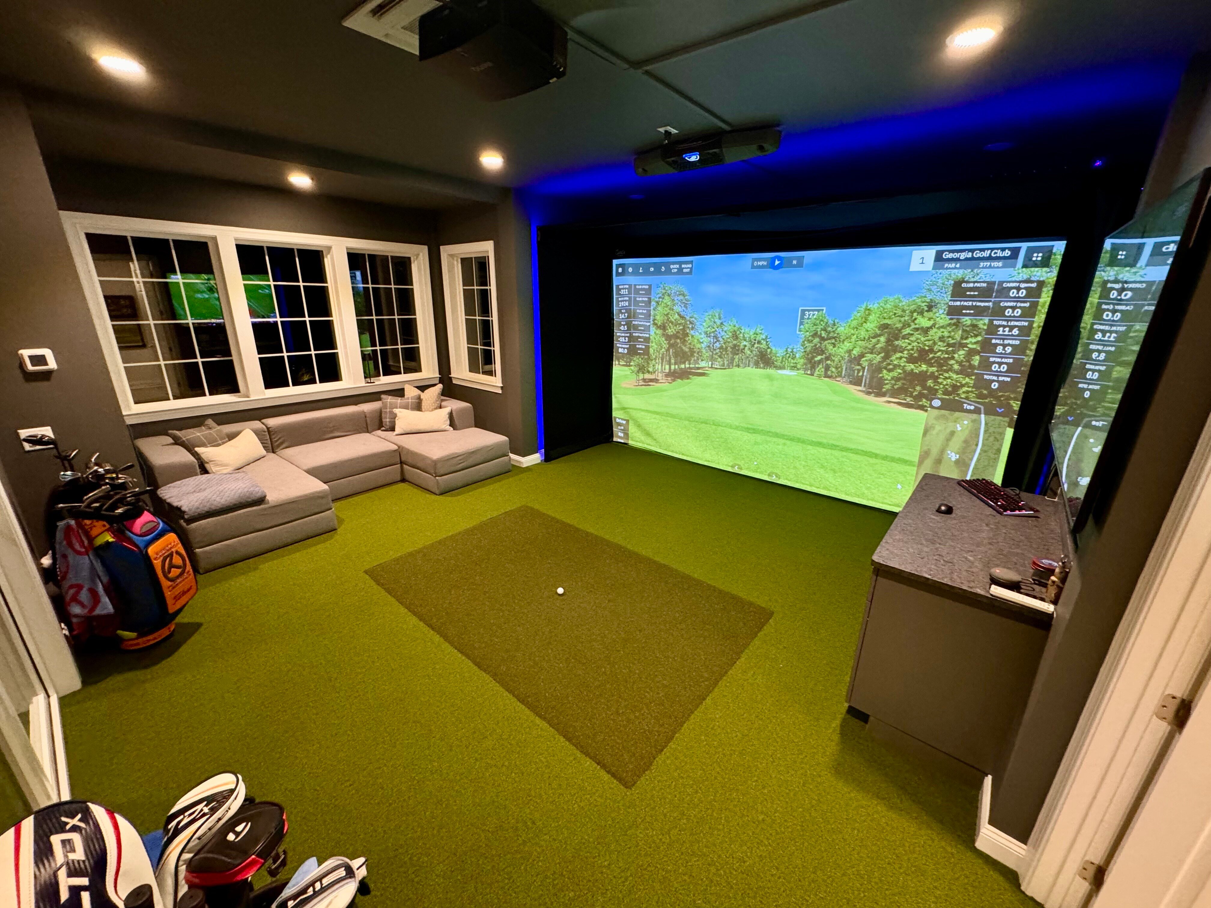 Home golf simulator room with sectional seating behind the hitting area