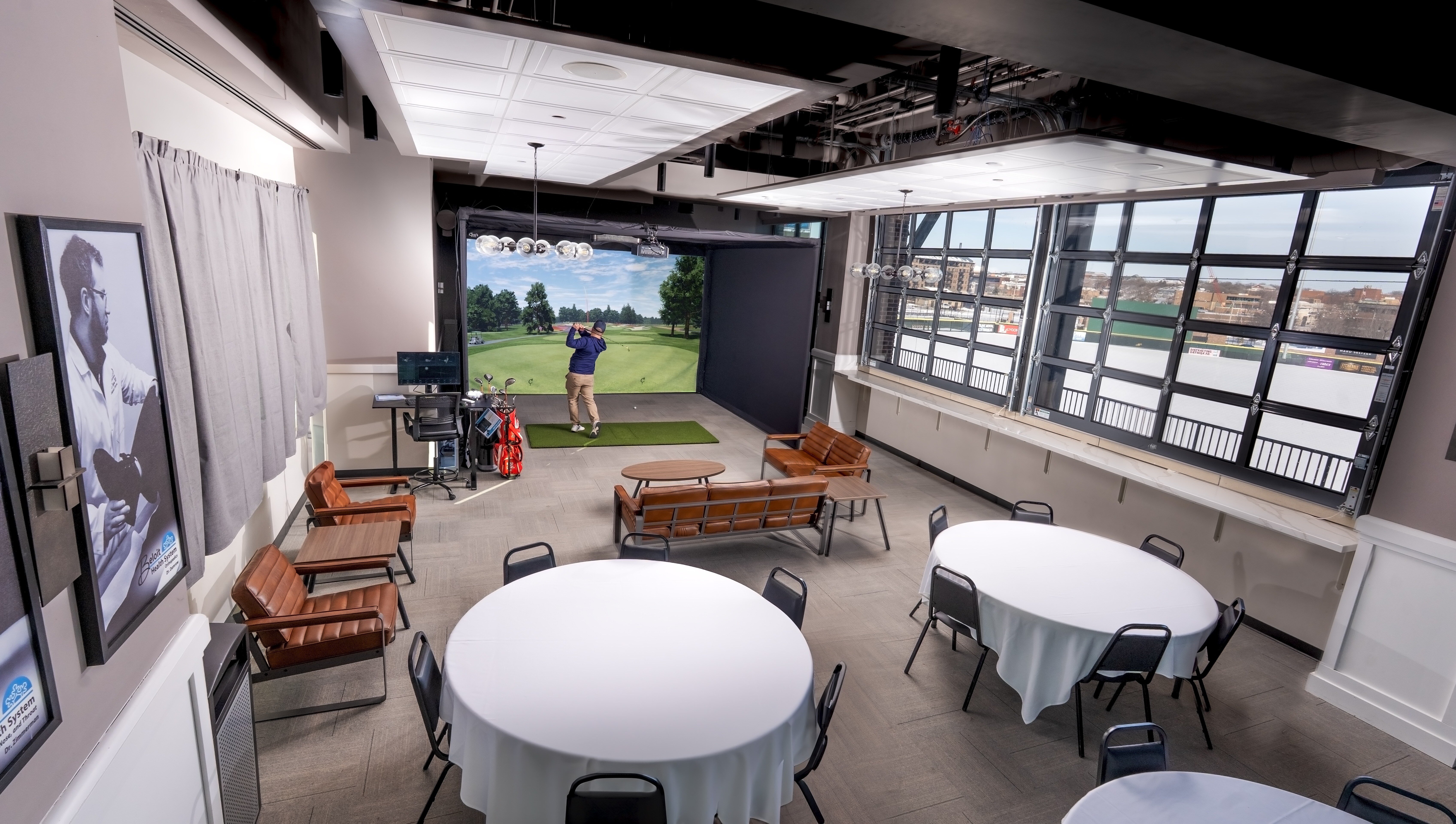 Commercial golf simulator event space with multiple seating areas for spectators and groups