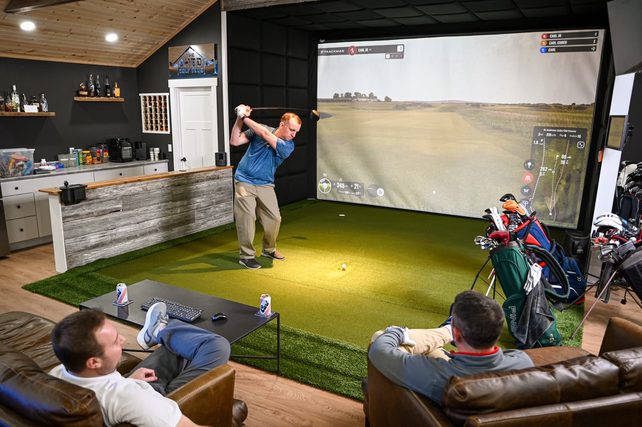 Golf simulator room with seating, TV, and lounge space for watching games