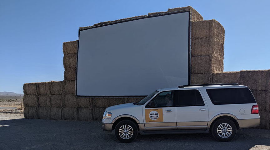 Large outdoor projection screen hung from hay bales